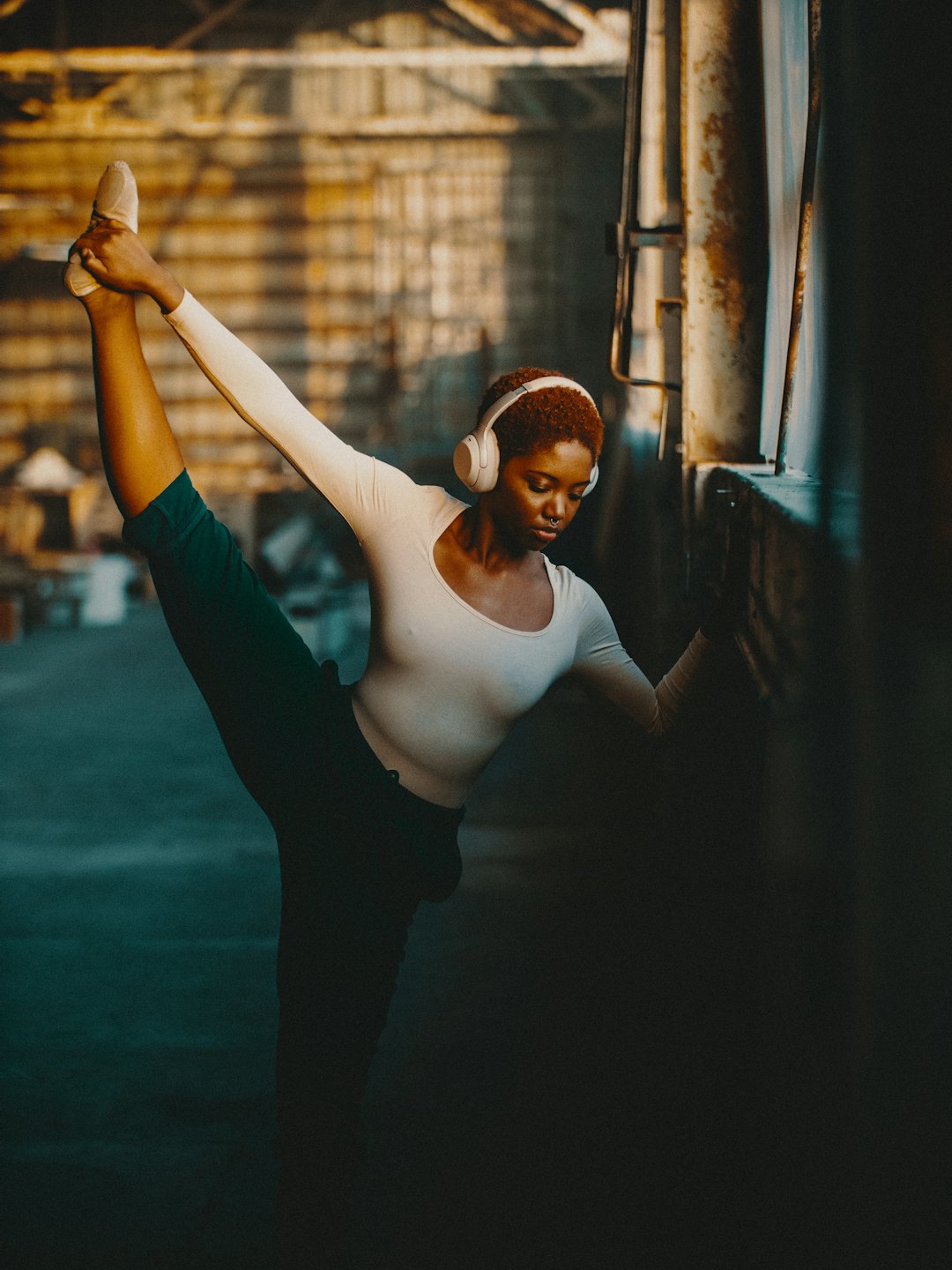 Woman in leotard stretches with headphones on.