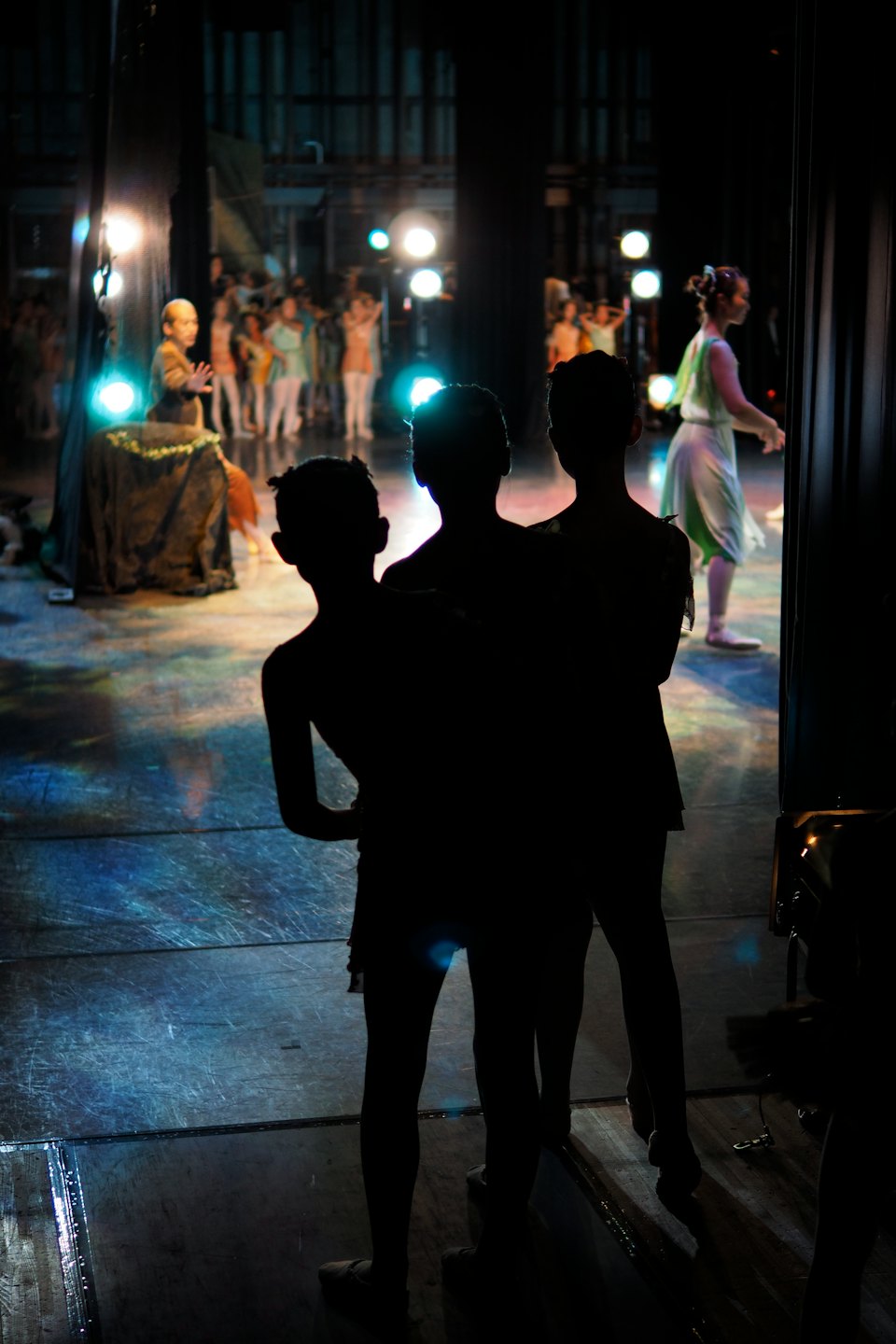 Performers in colorful costumes dance on a brightly lit stage.